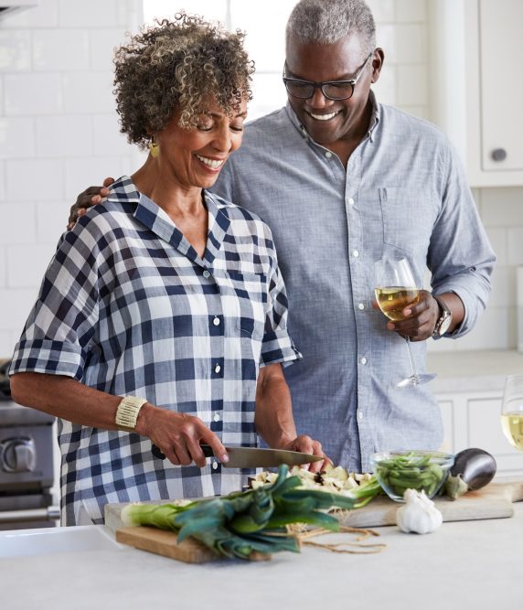Senior African American couple making a meal together in the kitchen smiling and enjoying each other's company