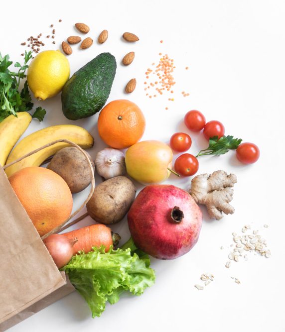Healthy food background. Healthy vegan vegetarian food in paper bag vegetables and fruits on white, copy space. Shopping food supermarket and clean vegan eating concept.